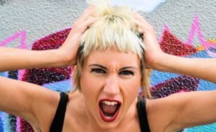Fotografie ženy, která křičí a drží se za vlasy