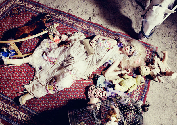 Žena ležící na dyvanu s hračkami, ptačí klecí a s hlavou koně