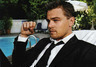 Leonardo DiCaprio sedící v obleku na lehátku u bazénu