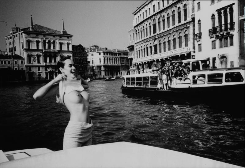 Černobílá fotografie ženy odhalující svá prsa na lodi
