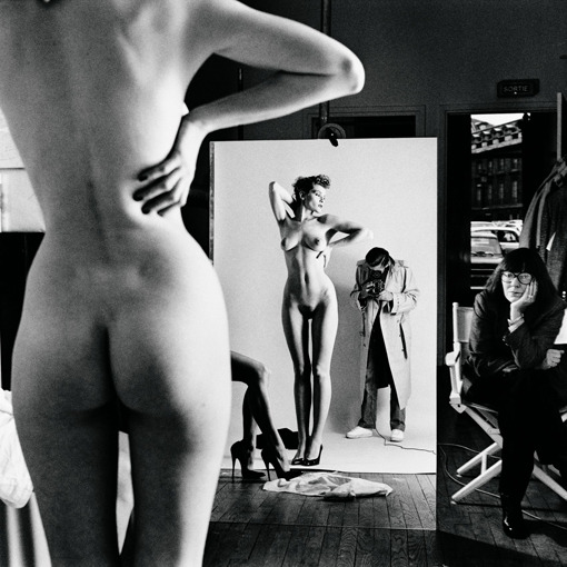 Fotograf fotí nahou ženu stojící před zrcadlem