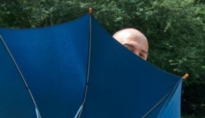 Fotografie zachycující muže schovávajícího se za deštník