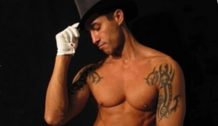 Muž propagující své nahé tělo a tetování za podpory klobouku na hlavě