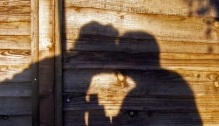Snímek zachycující polibek zamilované dvojice ve stínu