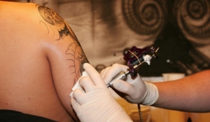 Fotografie zachycující tetování paže tatérem