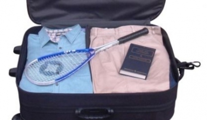 Fotografie rozevřeného kufru,kde je oblečení, kniha a tenisová raketa
