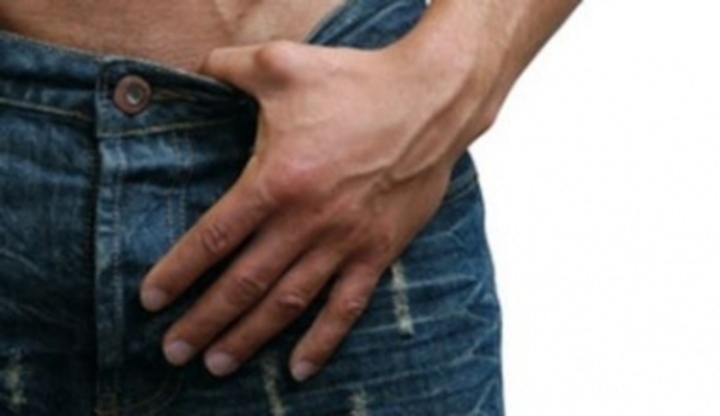 Detailní fotografie na mužský rozkrok v džínách, s prstem za opaskem