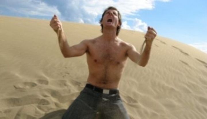 Muž klečící v písečné duně a prožívající emoce