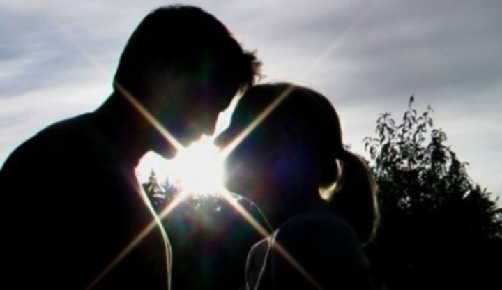 Detailní záběr na zamilovanou dvojici při západu slunce před společným polibkem