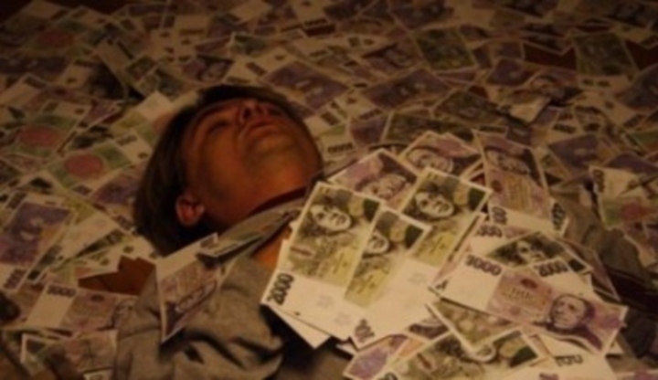 Fotografie muže, který leží v hromadě bankovek