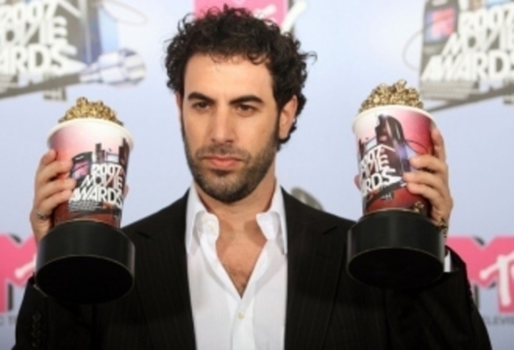 Herec Sacha Baron Cohen držící dvě ocenění v rukou