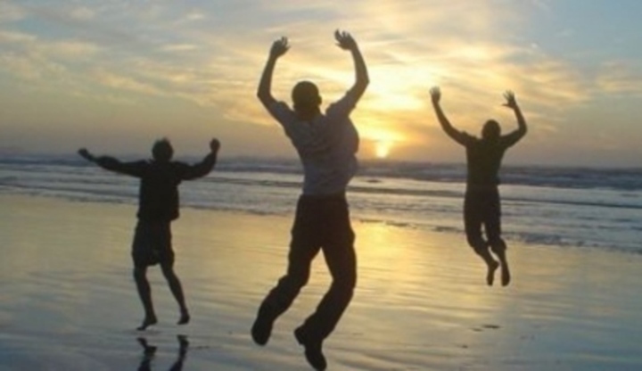 Fotografie tří mužů skákající na pláži při západu slunce