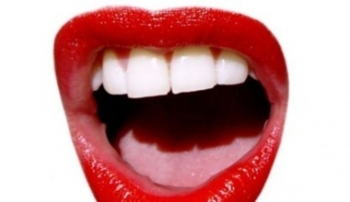 Detailní fotografie ženských úst s červenou rtěnkou