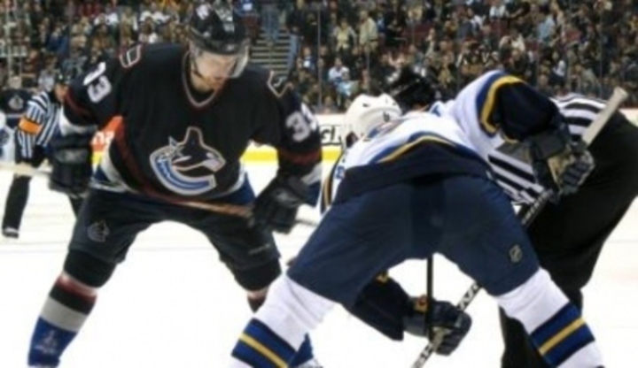 Snímek zachycující souboj o puk při ledním hokeji