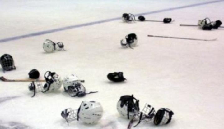 Fotografie zachycující přilby a hokejky na ledové ploše po hokejovém zápase