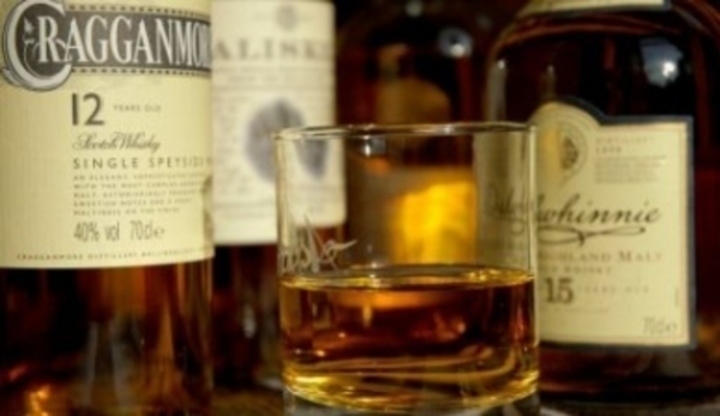 Sklenice na whisky mezi láhvemi alkoholu