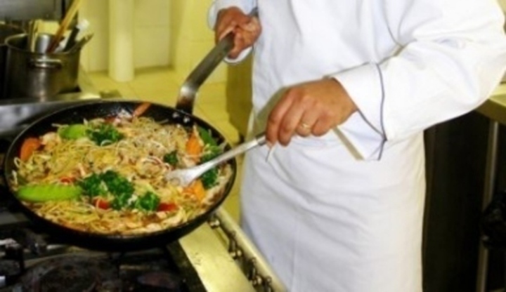 Detailní fotografie kuchaře, který vaří oběd v pánvi