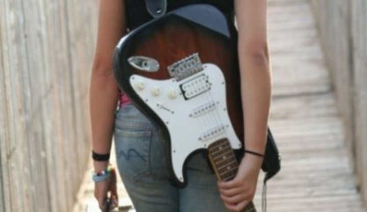 Fotografie ženy nesoucí na zádech elektrickou kytaru