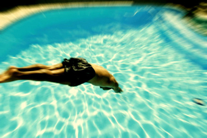 Fotka zachycující muže skákajícího do venkovního bazénu