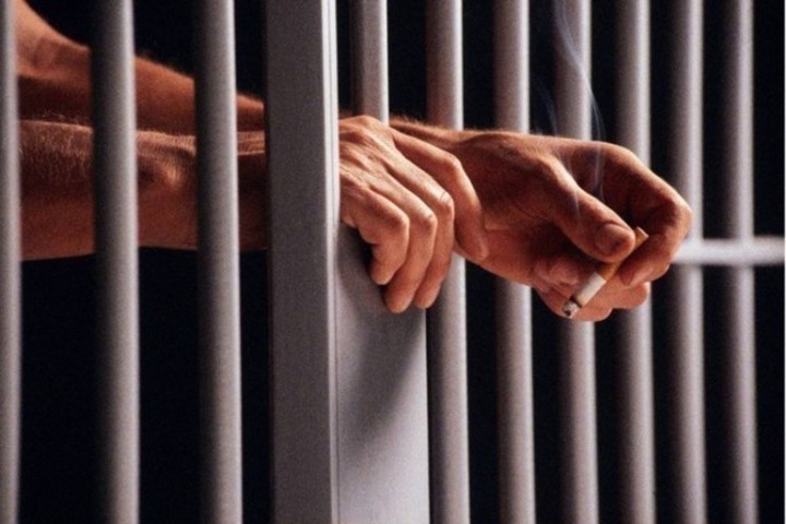 Detailní fotografie mužských ruk ve vězení