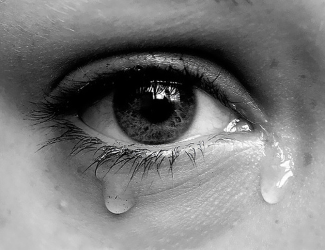 Černobílá fotografie s detailem na oko se slzou