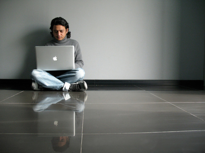 Fotografie muže sedící na zemi s počítačem v ruce