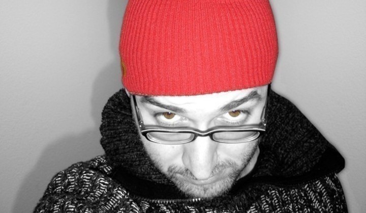 Černobílá fotografie muže s červenou čepicí