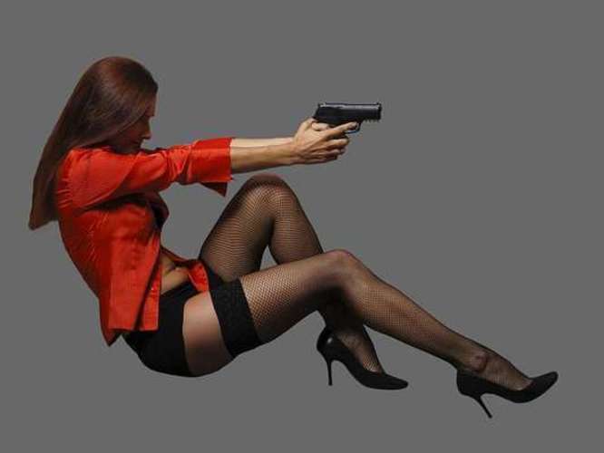 Fotografie ženy v podvazcích, v červeném saku a se střelnou zbraní v ruce