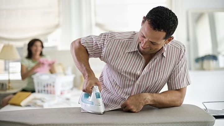Fotografie páru, kdy muž dělá domácí práce