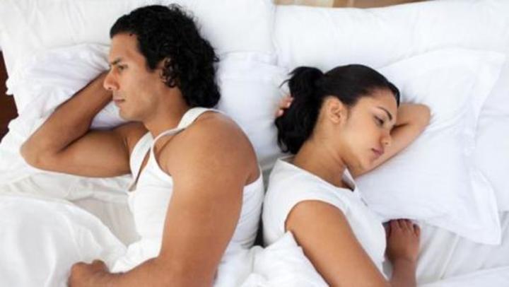 Fotografie mileneckého páru ležící zády k sobě v posteli
