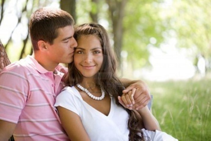 Fotografie dvojice, kdy muž drží ženu v ramenou a líbá ji na tvář