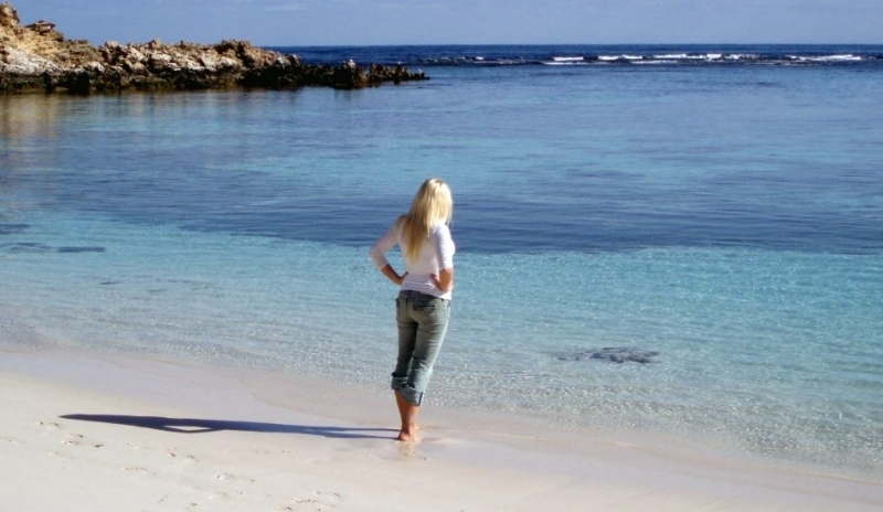Fotografie ženy stojící na pláži a dívající se na moře
