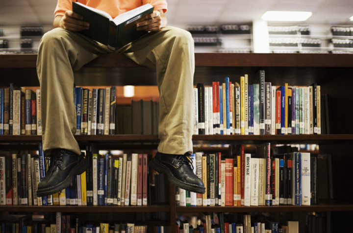 Fotografie muže, který sedí s knihou na knihovničce