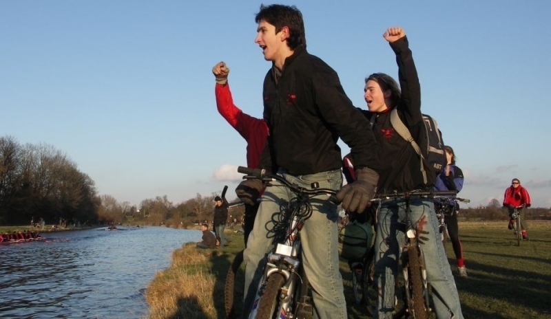 Skupinka lidí jedoucích na kole okolo řeky 
