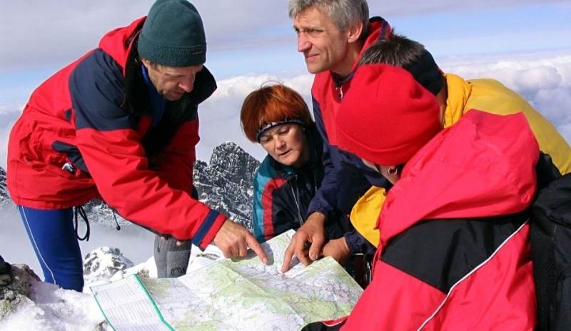 Skupinka lidí studuje mapu v horách