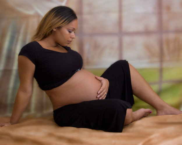 Fotografie těhotné ženy, držící se za břicho