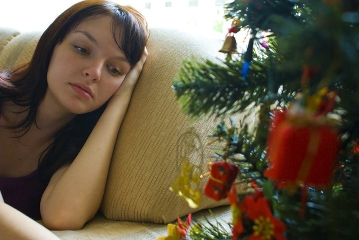 Unavená žena na sedačce u vánočního stromu