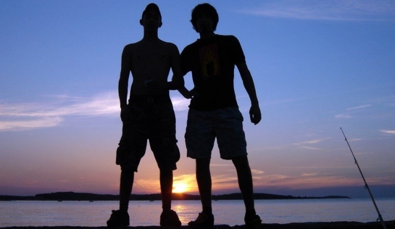Dva muži u moře pozorující západ slunce