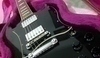 Detailní fotografie na černou kytaru v růžovém pouzdře