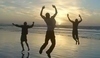Fotografie tří mužů skákajících na pláži při západu slunce