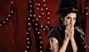 Amy Winehause stojí před mikrofonem s rukama na puse