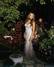 Krásná Amanda Bynes v dlouhých šatech stojící v květinové zahradě
