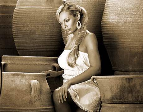Lucie Borhyová v bílých šatech sedí mezi hliněnými džbány
