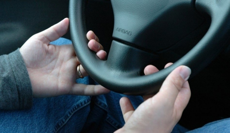 Snímek zobrazující ruce držící volant 