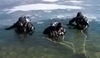 Fotografie tří potápěčů vycházejících z vody