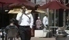 Fotografie muže kráčejícího po ulici s telefonem v ruce