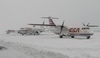 Fotografie tří letadel na zasněženém letišti