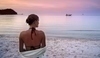 Žena stojící na písku a dívající se na moře
