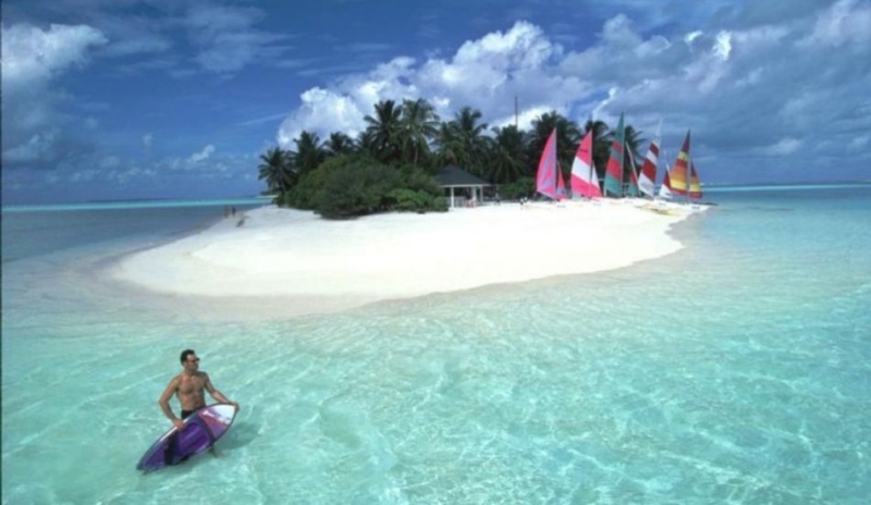 Fotografie zobrazující ostrov a muže se surfem