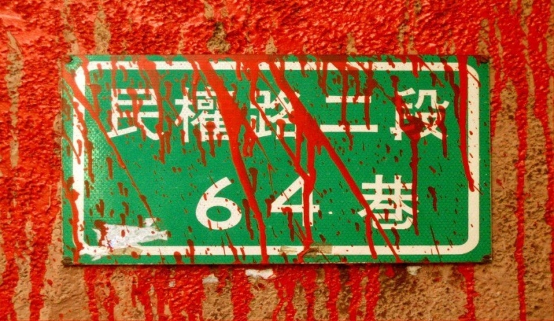 Zelená tabulka na zdi pocákaná červenou barvou